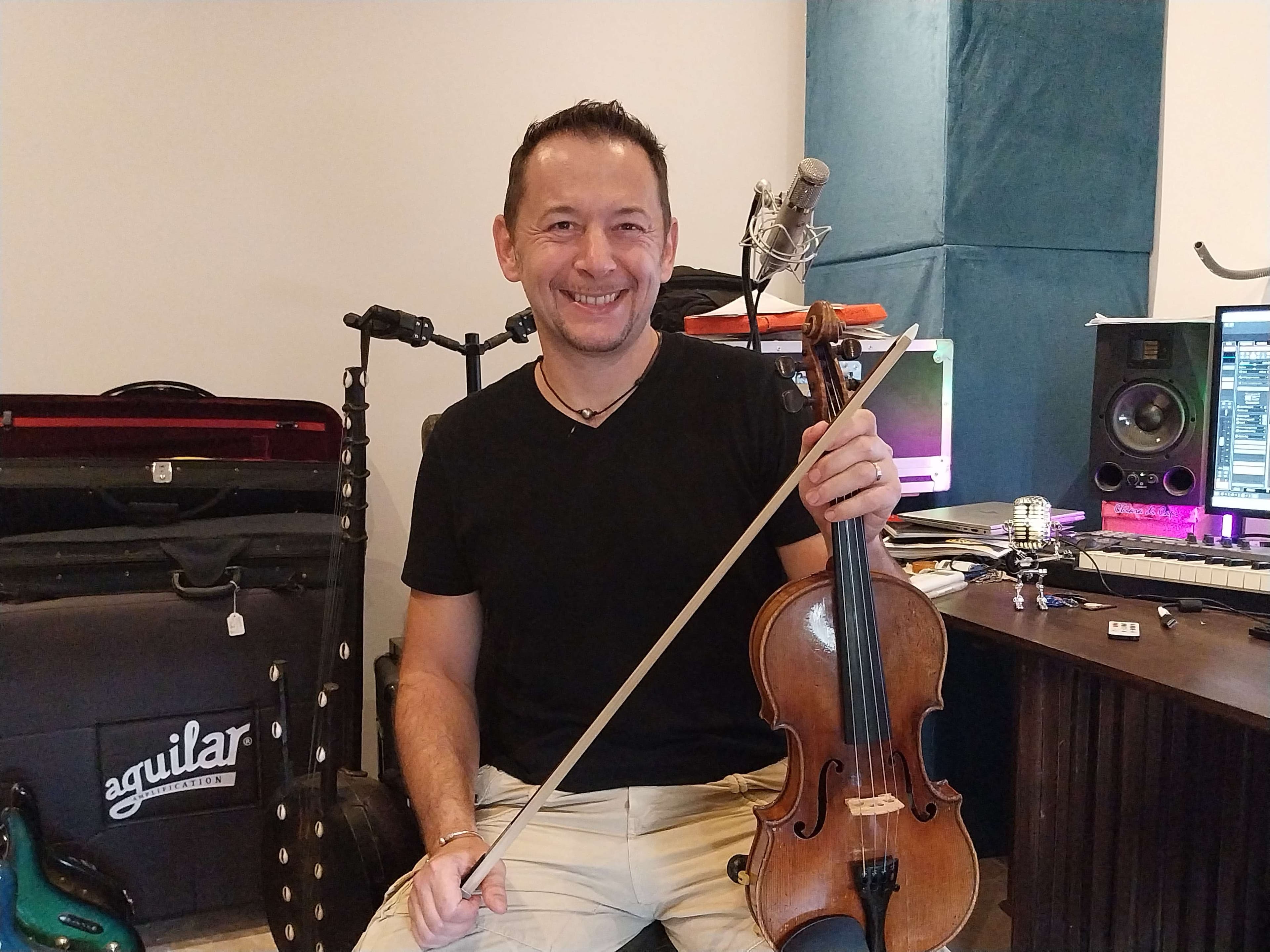 a man sitting in front of a violin in a recording studio